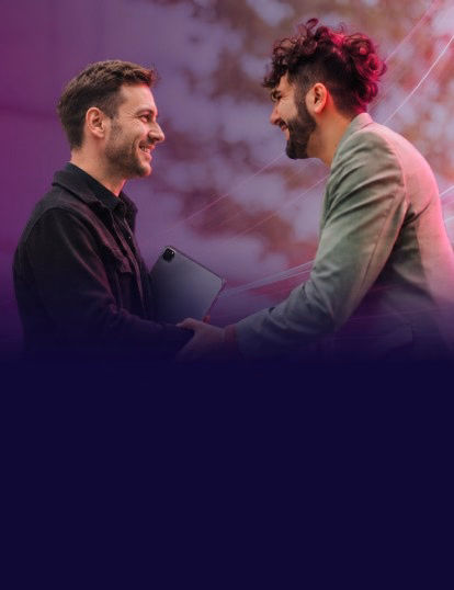 Two smiling traders shaking hands, one holding a tablet