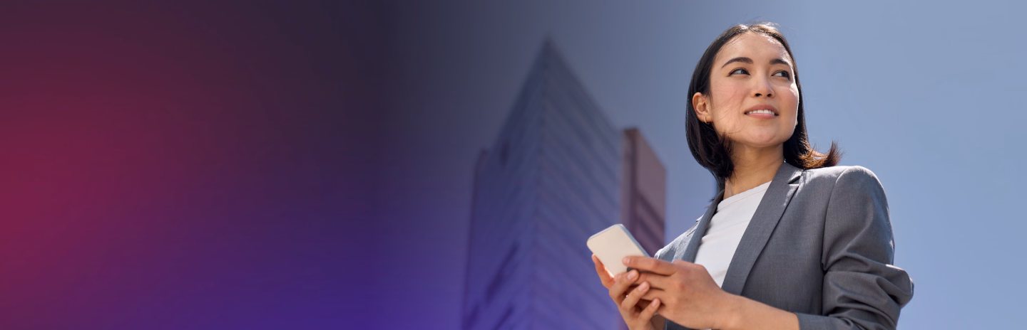 Smiling businesswoman holding a phone with city buildings in the background